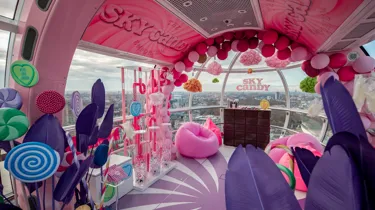 London Eye Pod Capsule decorated in different pink and purple tones. With props of sweets and signs in pink reading the sky candy emporium.