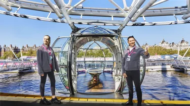 Two twin girls laying on the grass in front of London Eye