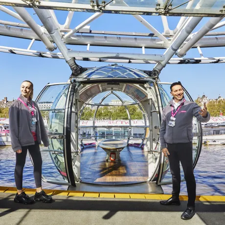 Two twin girls laying on the grass in front of London Eye