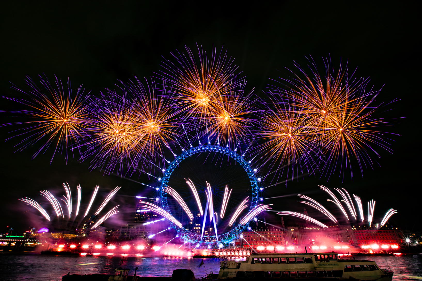 The London Eye lit up in blue with fireworks bursting in the night sky during New Year's Eve 2024 celebrations