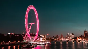 A picture of the London Eye in the night time lit up in pink