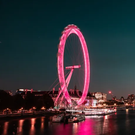 A picture of the London Eye in the night time lit up in pink